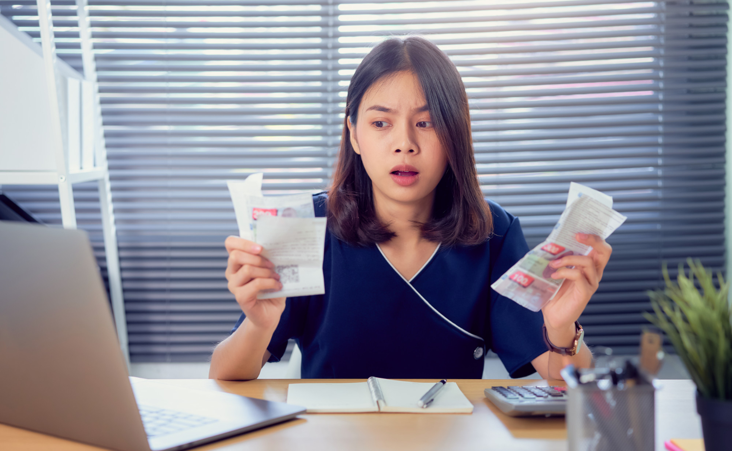 shocked-face-asian-woman-hand-holding-expense-bill-calculation-about-debt-bills-monthly-table-home-office